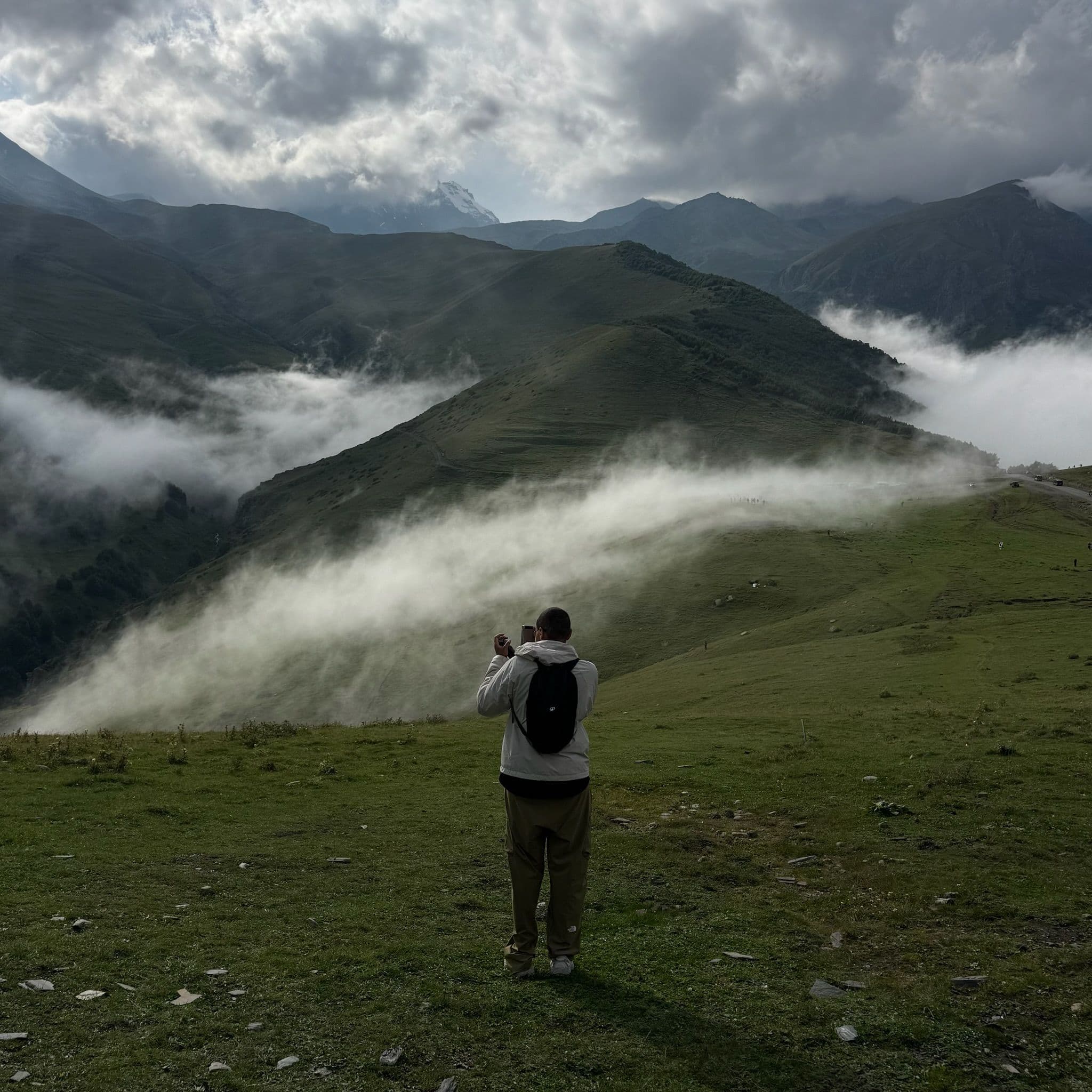 Lauren standing in front of the mountains and rolling hills near the Gergeti Trinity Church