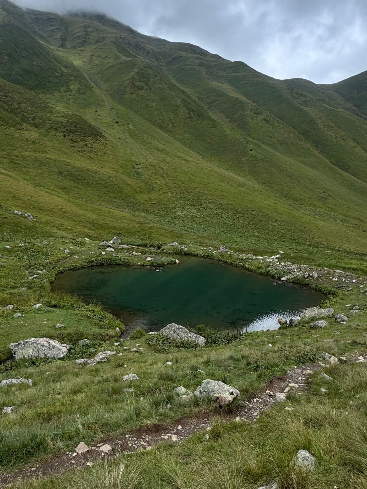 Chaukhi Lake nestled in the green pastures of the valley